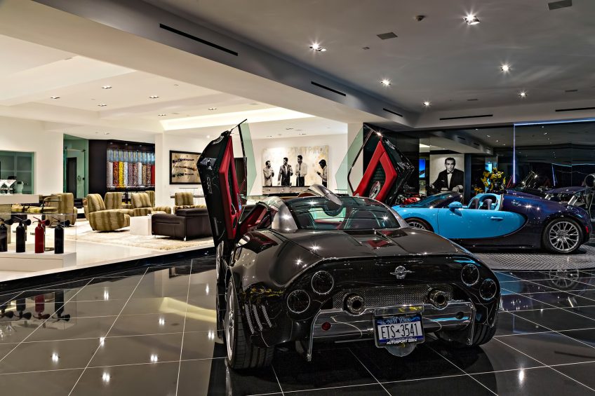 Glass-walled car gallery inside 1181 N Hillcrest Road in Beverly Hills, with the candy wall in the living area beyond